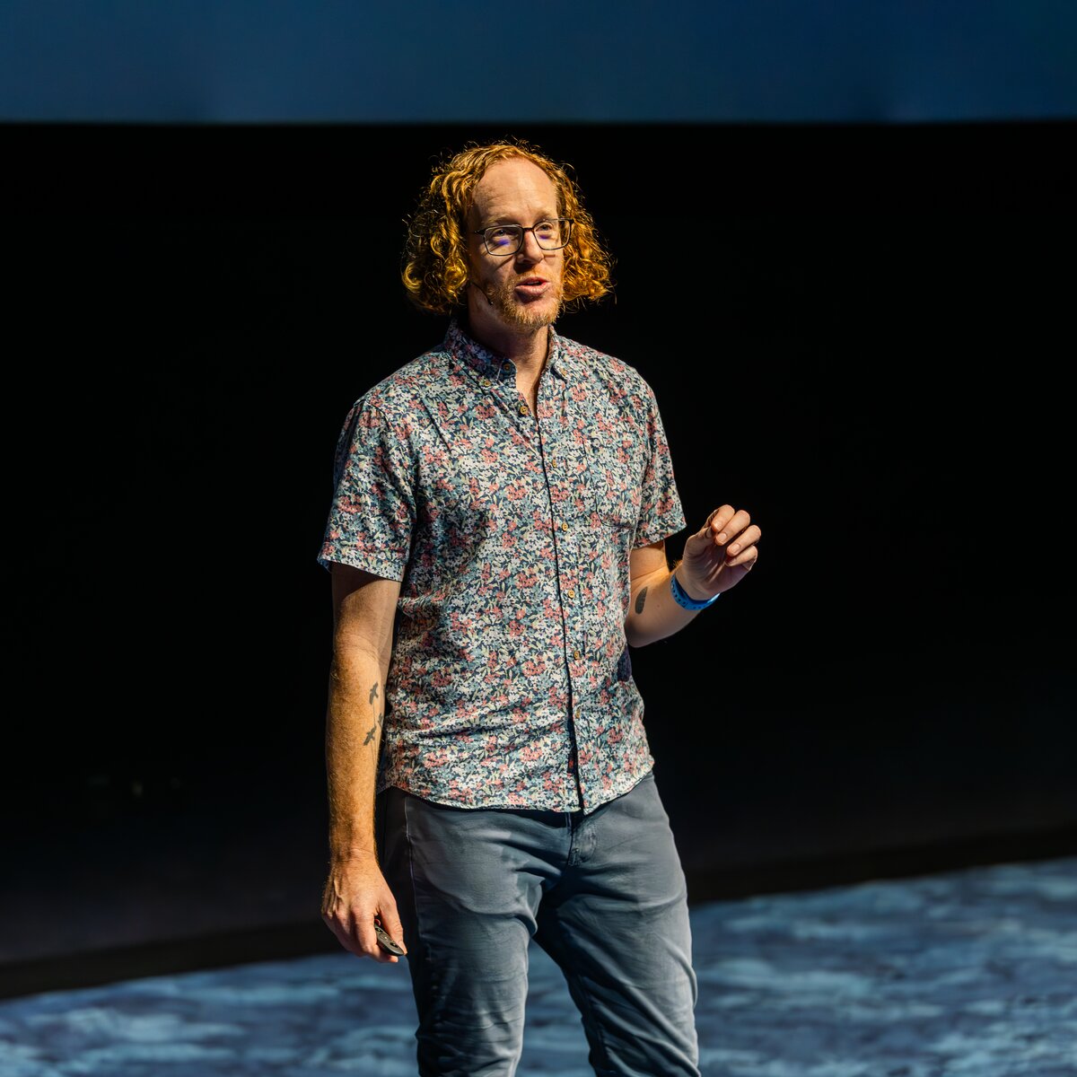 Robby Russell on stage mid-talk, presentation remote in hand